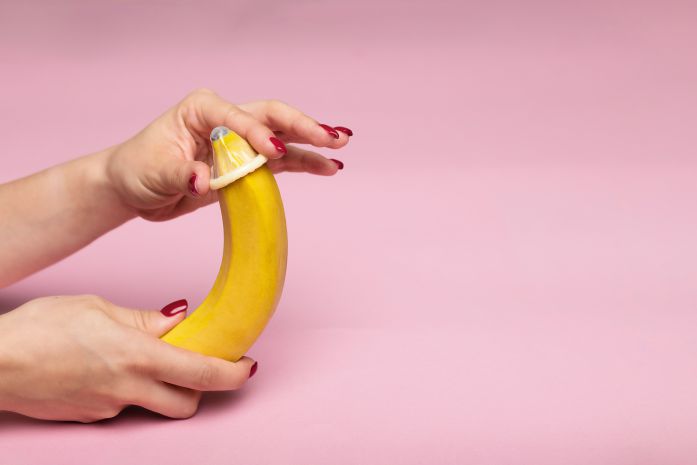 banana con preservativo e mano donna